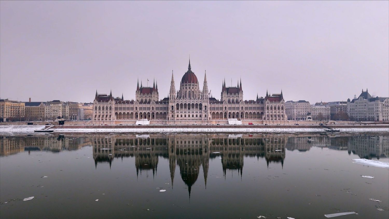 A panoramic view of the Hungarian Parliament Building reflected in the Danube River during different times of day.