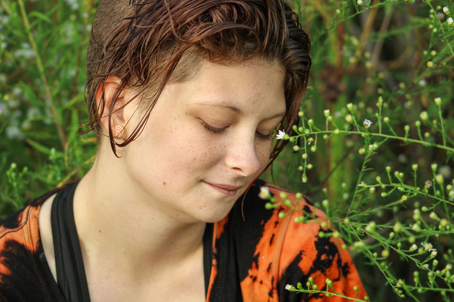 A dreamy portrait in a garden with delicate white flowers and greenery in soft natural lighting.