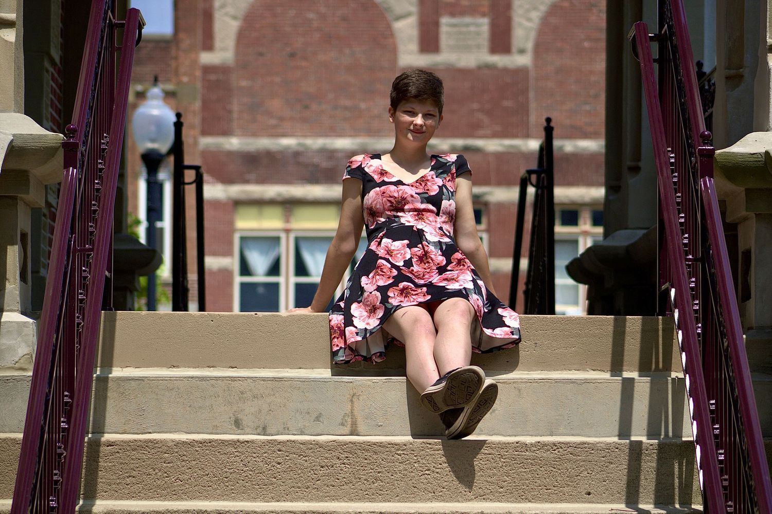 Students sitting on outdoor steps at a university campus on a sunny day.