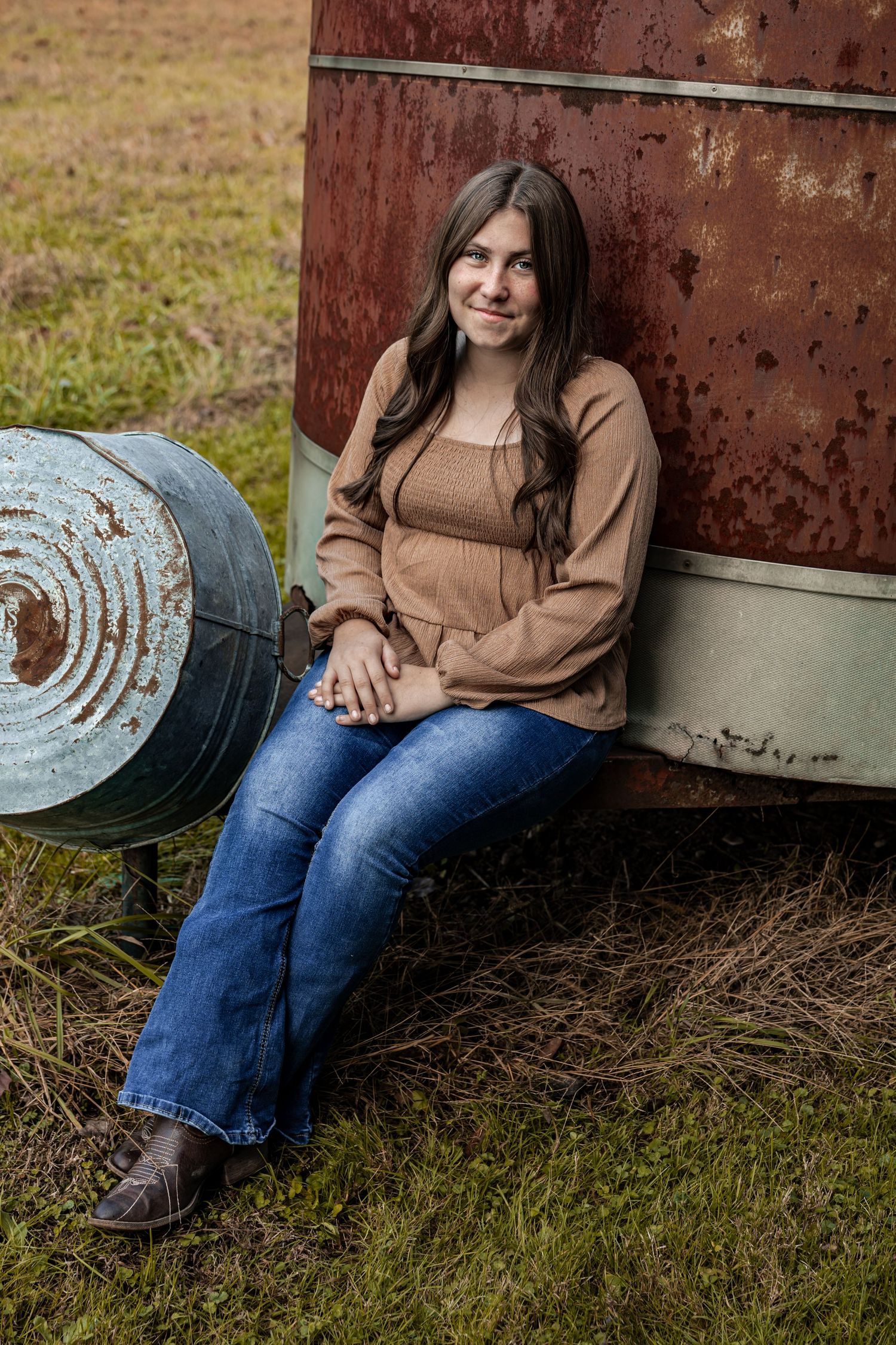 A rustic outdoor portrait session featuring someone sitting against a weathered metal door in casual attire.