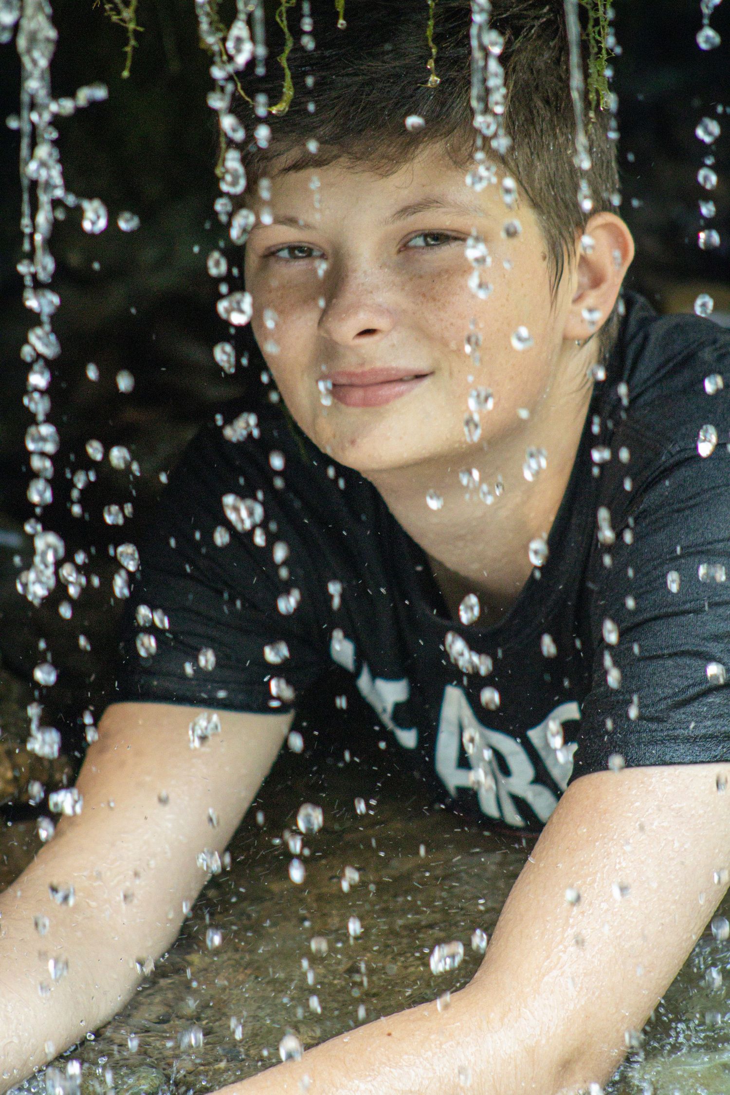 Water droplets splash and sparkle in a dynamic close-up portrait against a dark background.