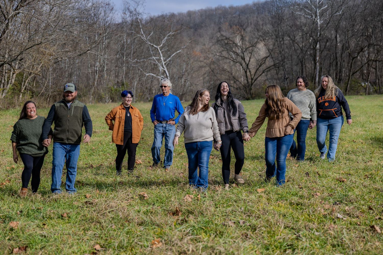 Group of people walking together through an autumn field on a cloudy day.