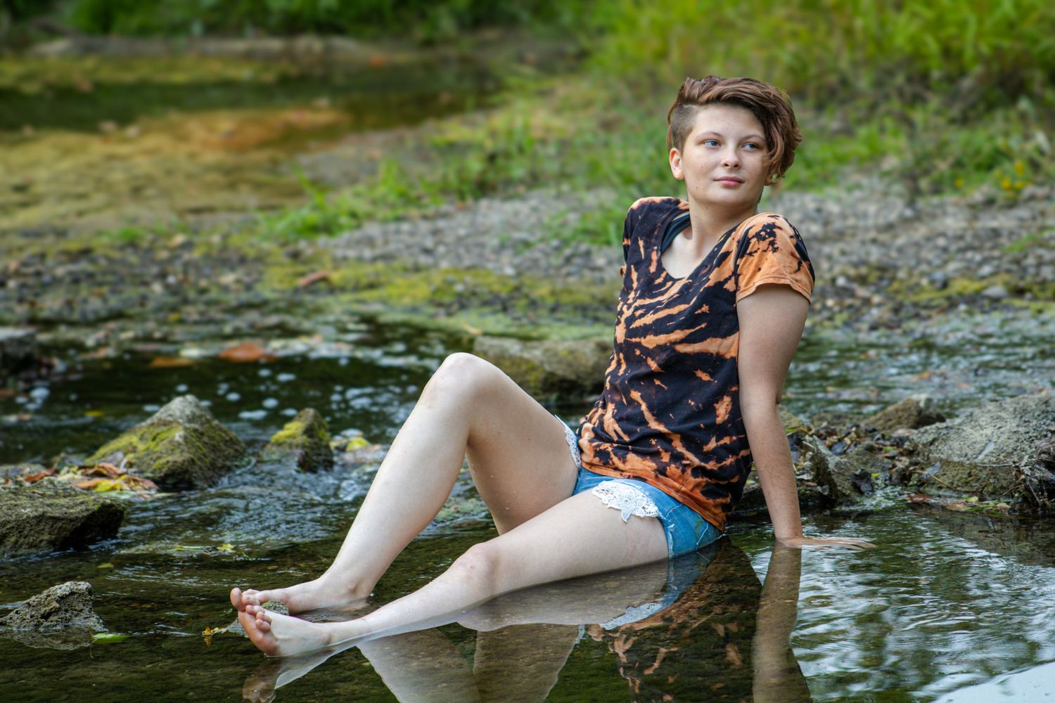 A child plays and splashes in a shallow stream on a warm summer day, exploring the natural surroundings.