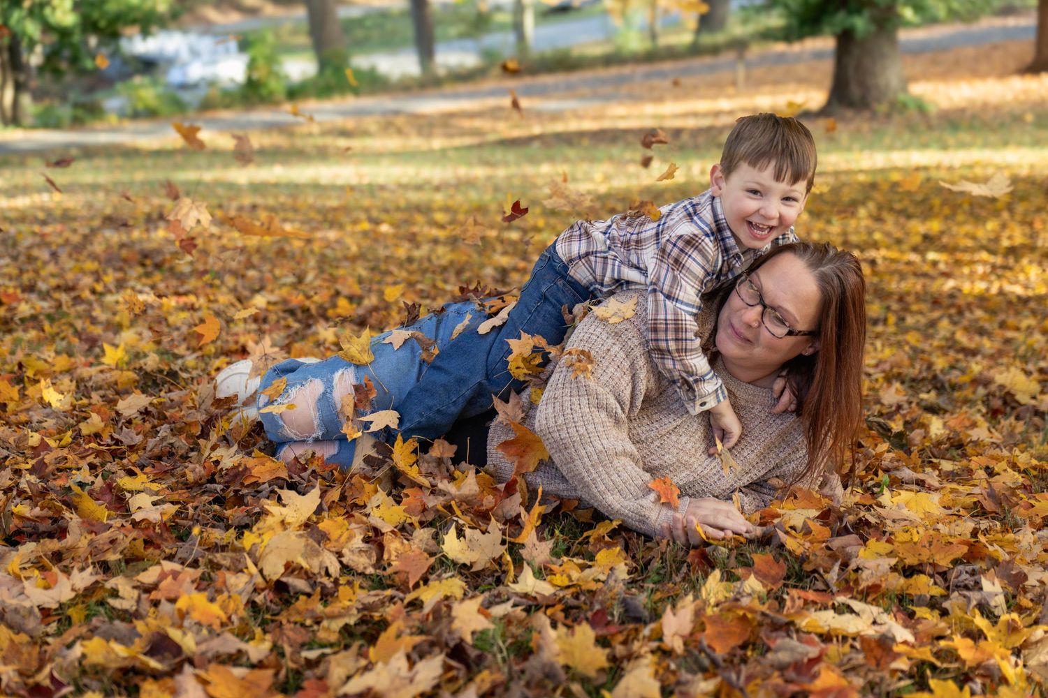 Couple lying in autumn leaves during romantic fall photoshoot in a park.