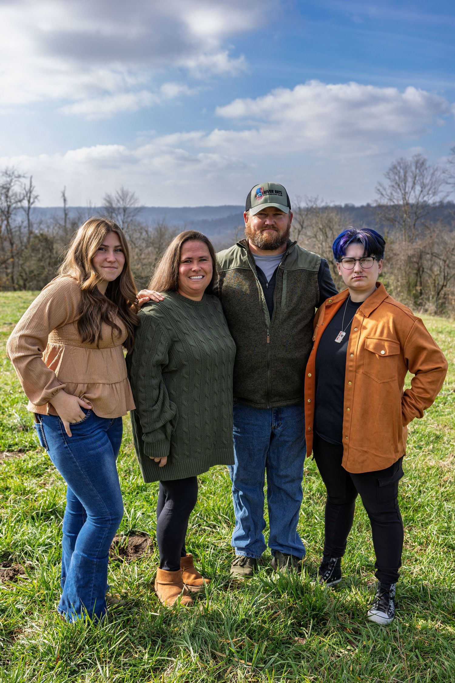 Group of friends pose together on a grassy hillside on a sunny day.