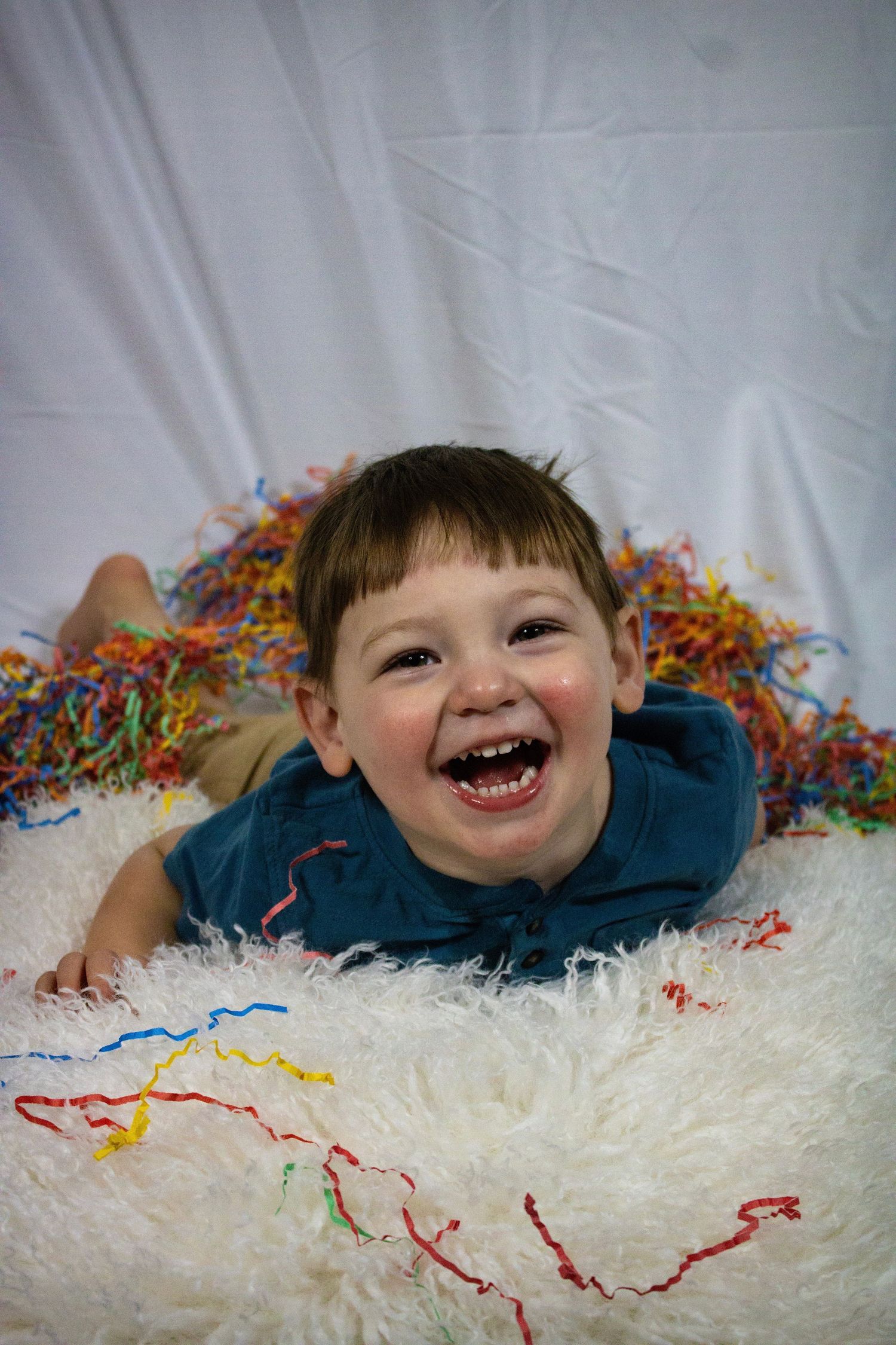 A series of three joyful photos showing someone lying on a white fluffy rug with colorful confetti scattered around.