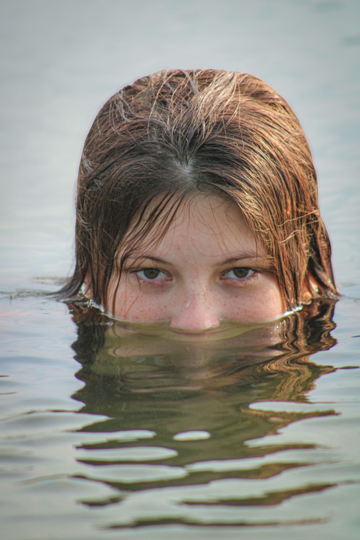 A person's head emerges from still water in a series of sequential photos showing different angles and positions.