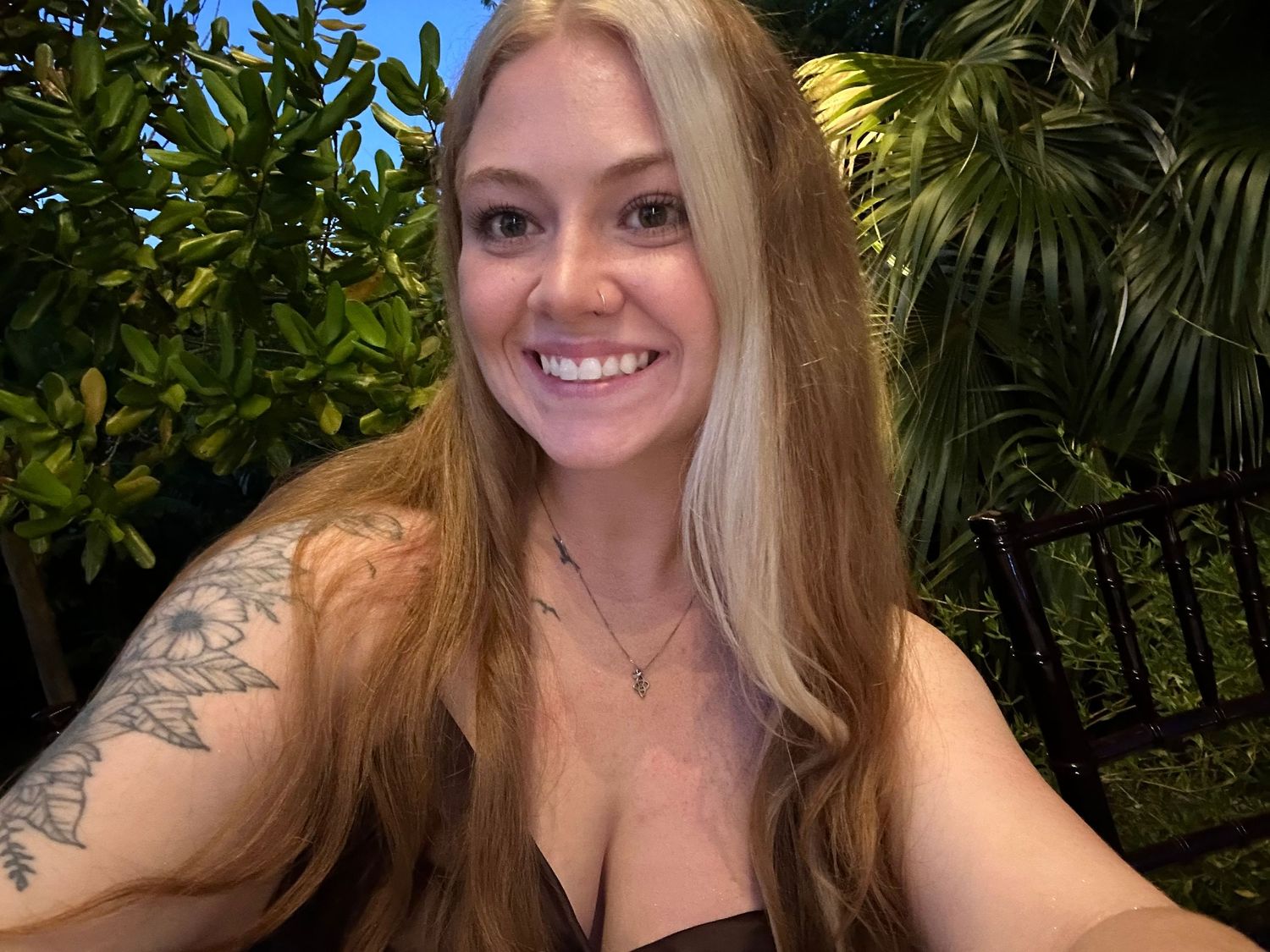 Seven selfie photos showing a person with long blonde hair posing outdoors against a backdrop of tropical foliage.