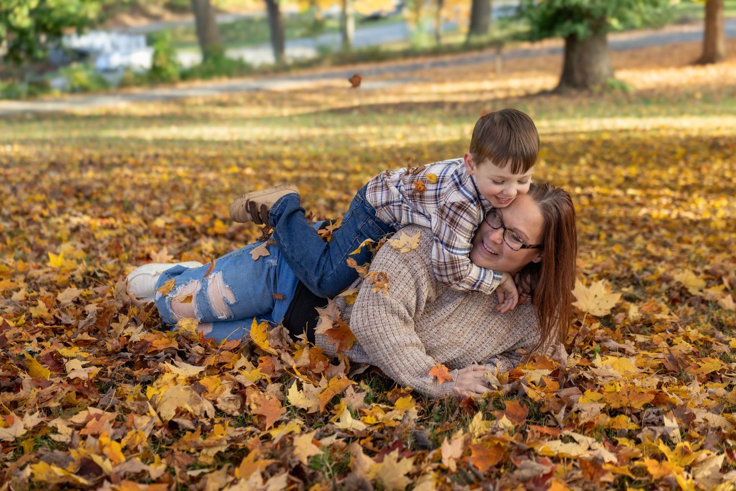 Couple lying together in fallen autumn leaves at a park on a sunny day.