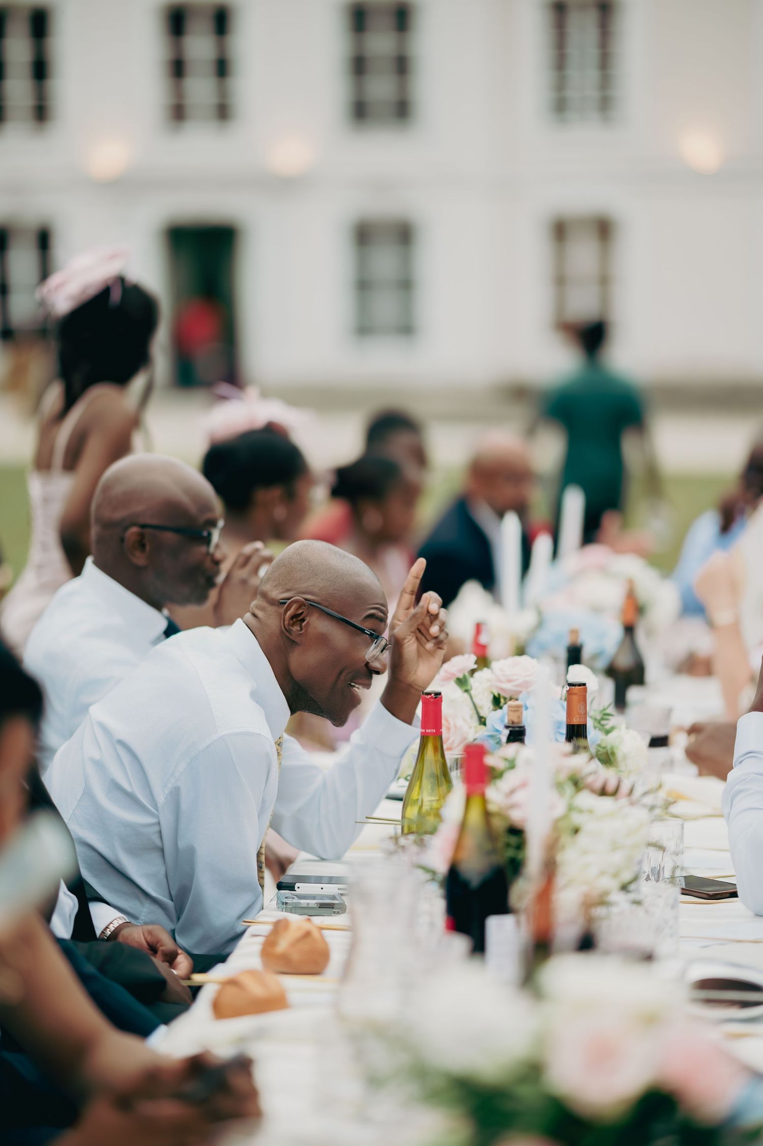 Wedding guests enjoying lively conversation at elegant outdoor reception dinner table.