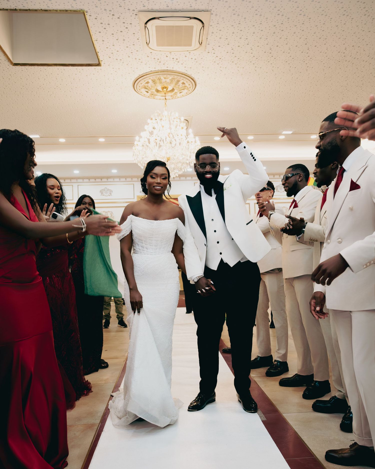 Joyful newlywed couple making grand entrance at elegant wedding reception with guests celebrating.