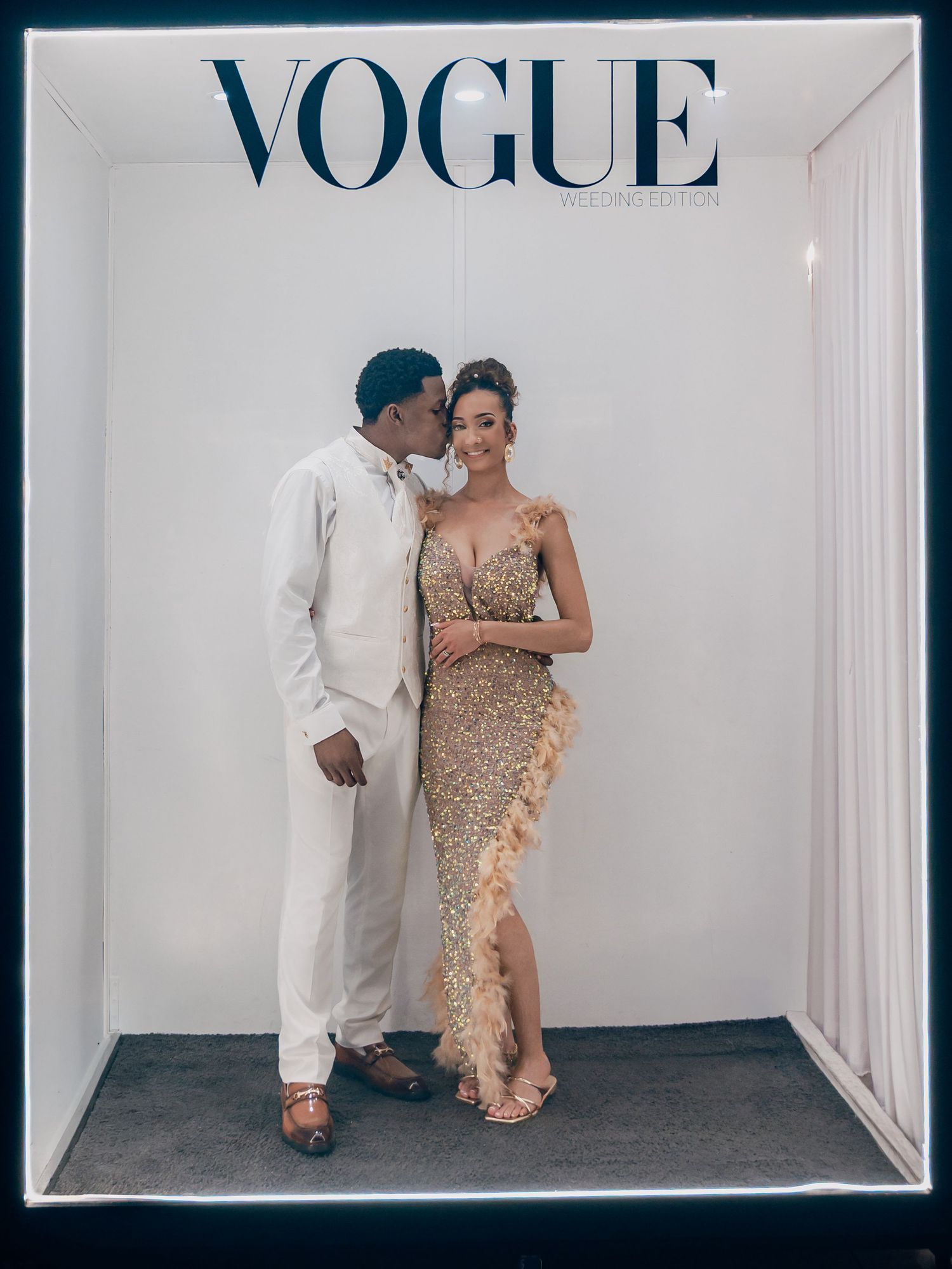 Bride in gold sequin gown and groom pose together in a Vogue magazine photo booth.