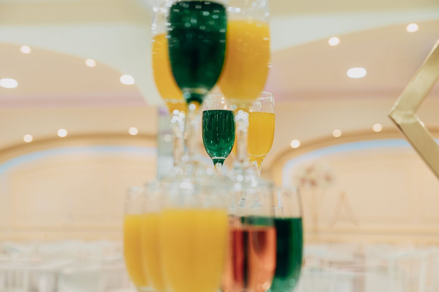 Elegant champagne flutes filled with orange juice and colorful drinks arranged for a wedding reception.