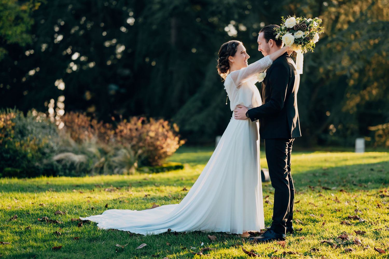 Bride and groom share romantic moment outdoors in golden hour sunlight after wedding.
