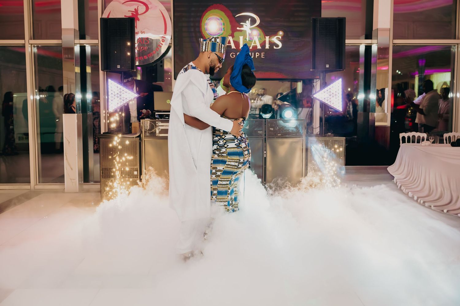 Couple shares first dance surrounded by dramatic fog effect at African wedding reception.