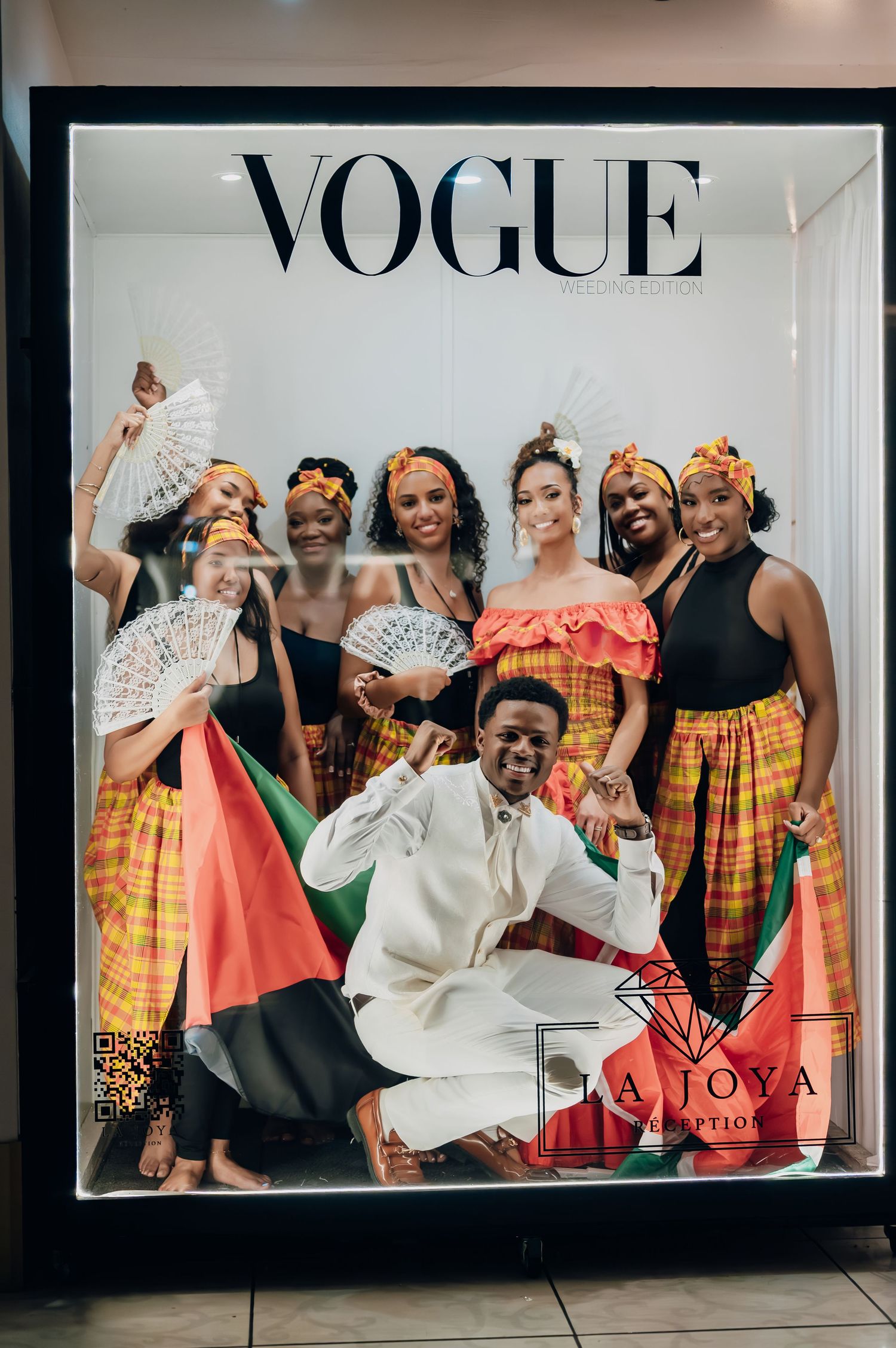 Group of women in colorful Caribbean traditional attire posing in a Vogue magazine cover display at La Joya reception.