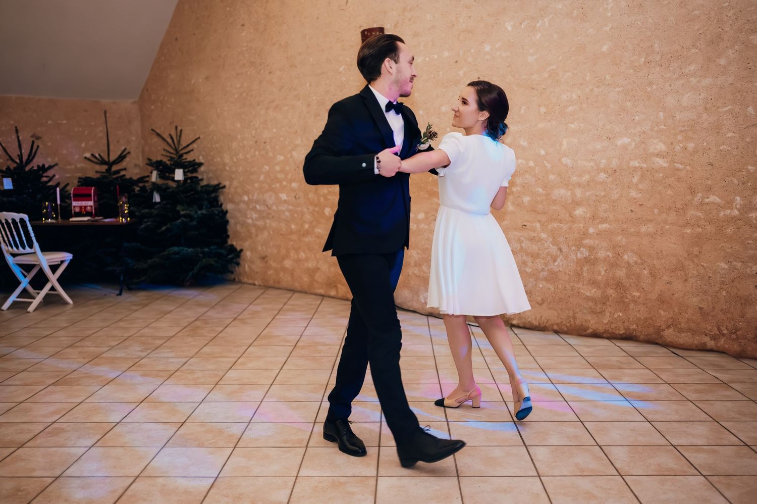 Bride and groom share their first dance in a elegant wedding venue with tiled floors.