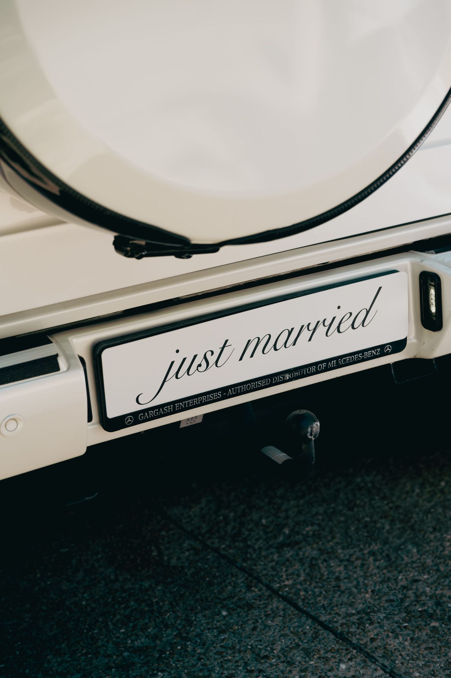 Close-up of just married license plate on white luxury Mercedes G-Wagon wedding getaway car.