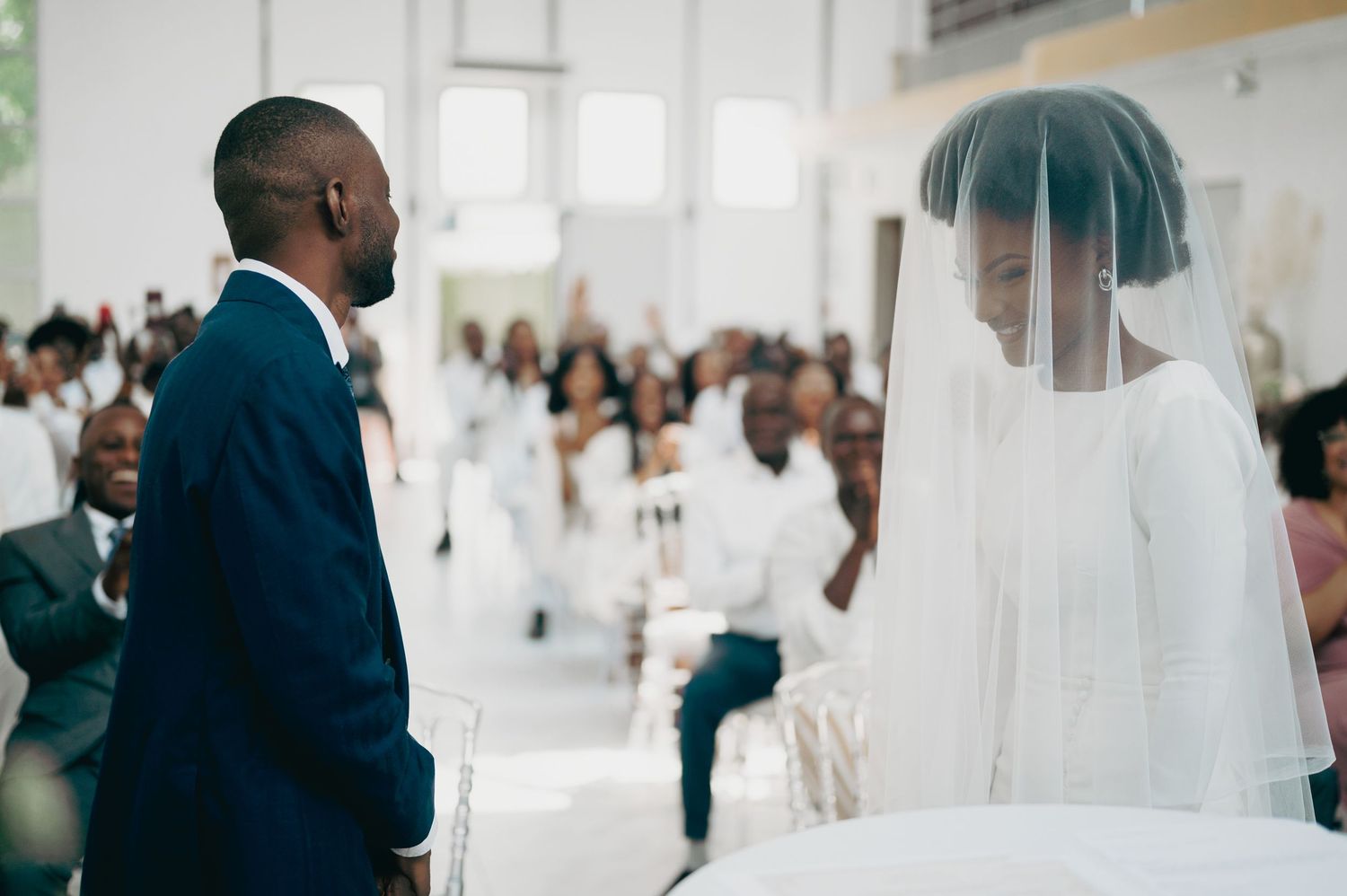 Bride in white veil and groom in navy suit exchange vows at a church wedding ceremony.