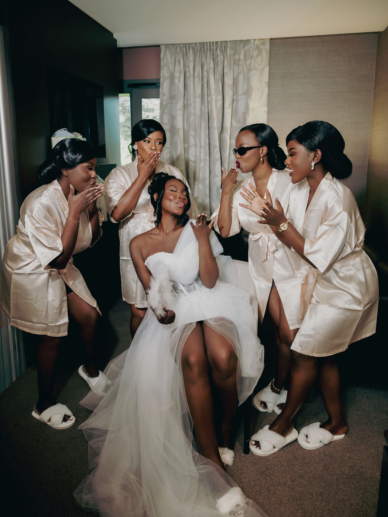 Bride in white corset tulle gown surrounded by five bridesmaids in champagne satin robes.