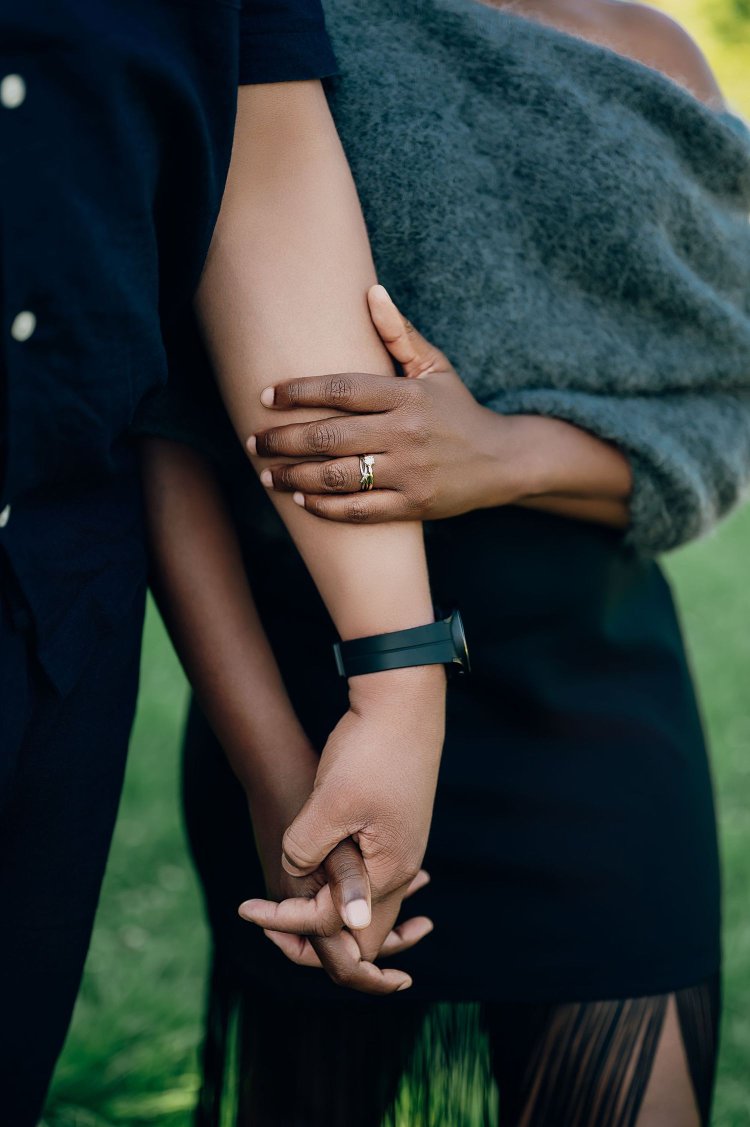 Close-up of engaged couple holding hands showing diamond engagement ring and smartwatch.
