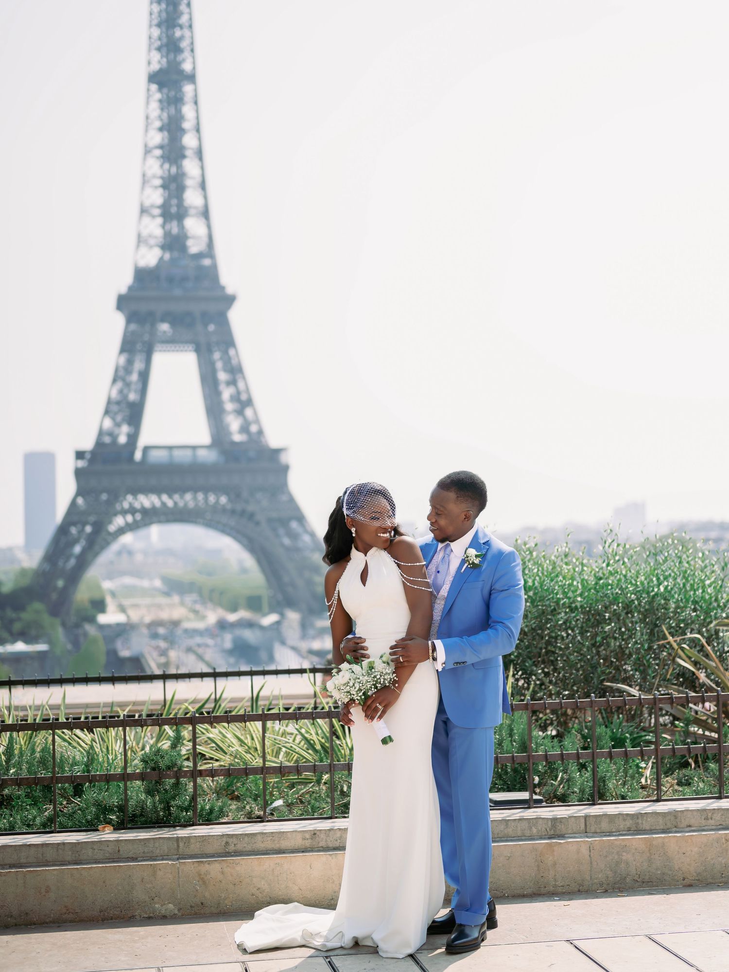 Newlywed couple poses romantically in front of the Eiffel Tower in Paris, France.
