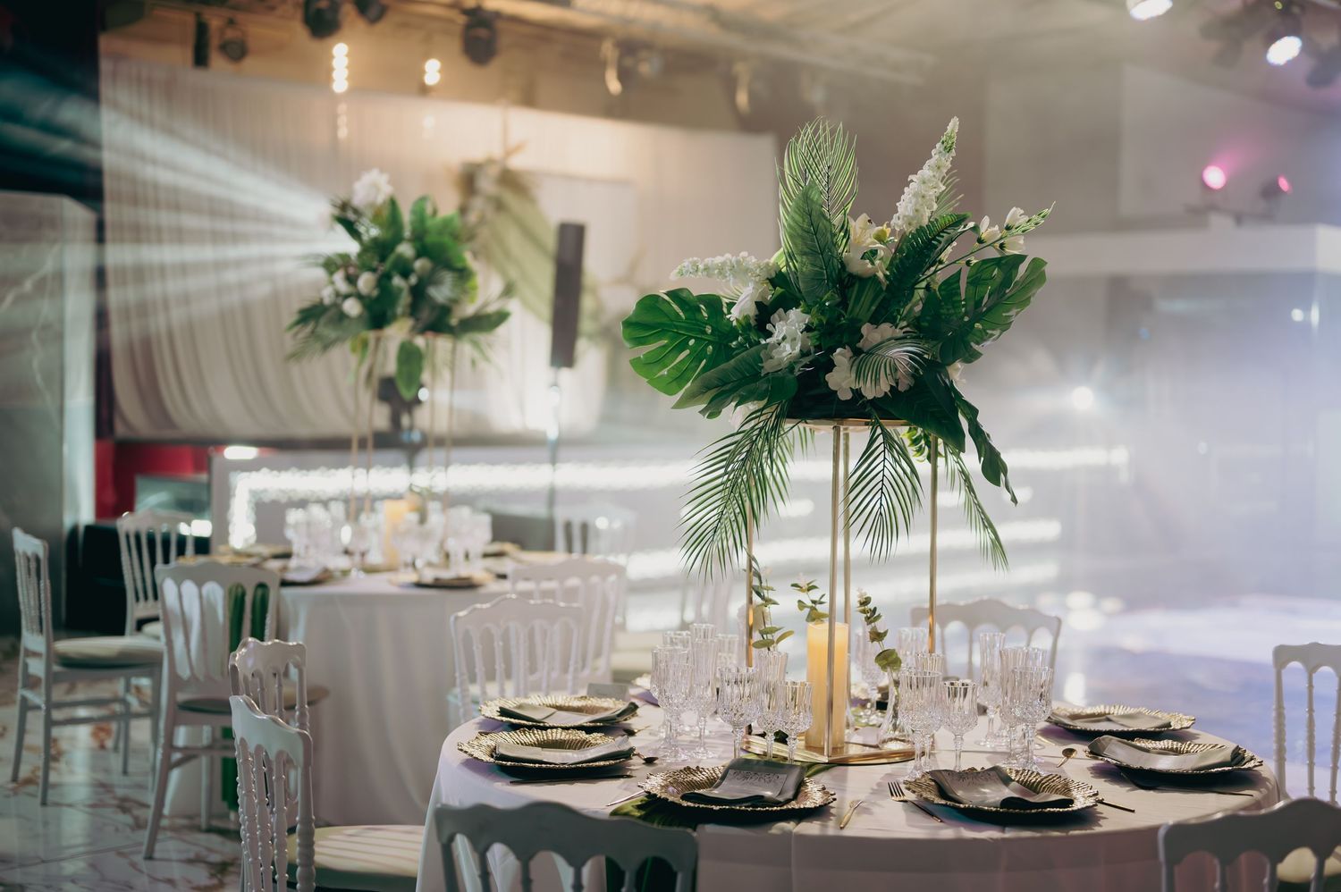 Elegant wedding reception tables adorned with tall tropical floral centerpieces and candles.