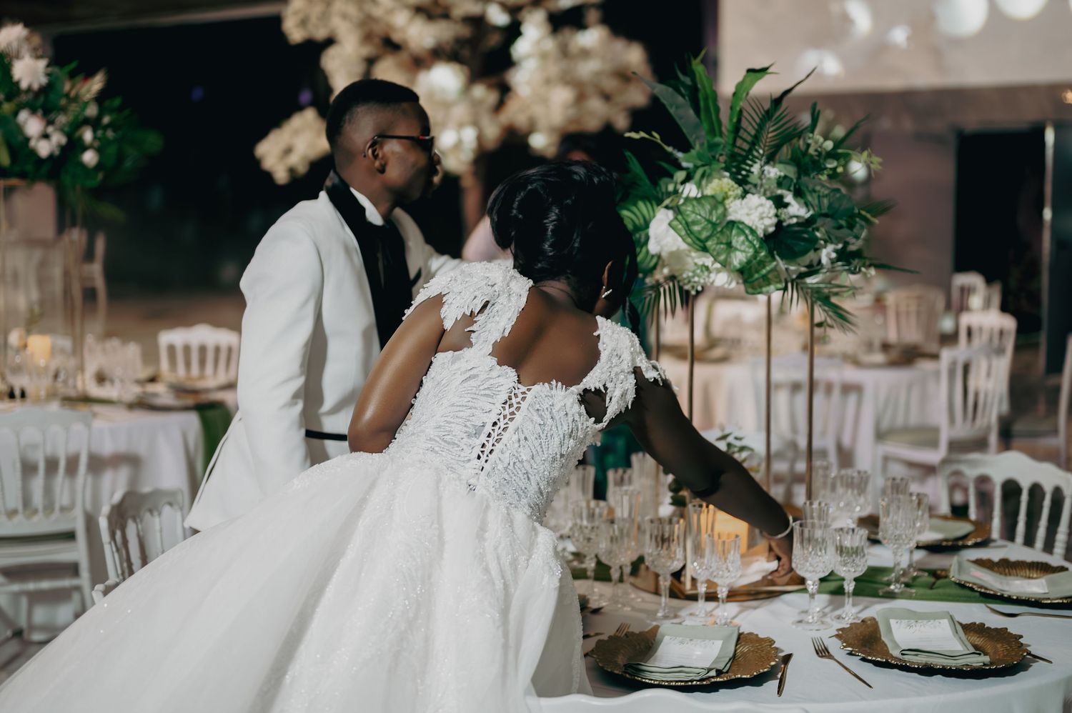 Bride and groom share intimate moment at elegantly decorated wedding reception table.