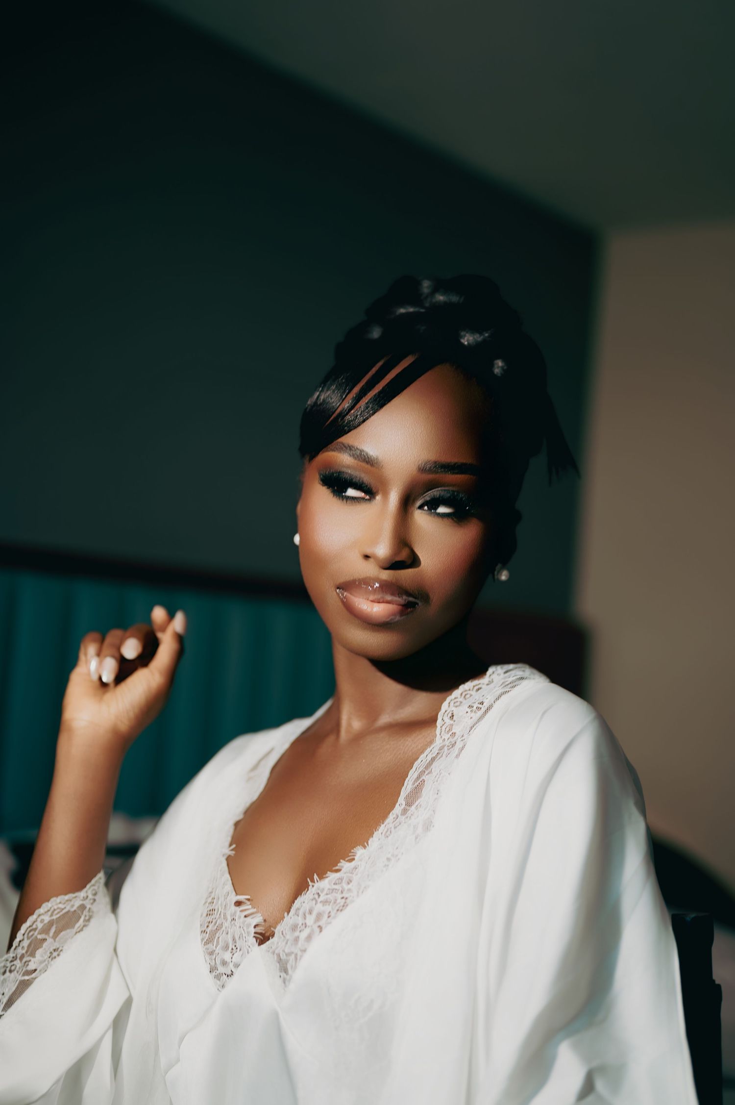 Stunning bride in white lace robe posing with dramatic bridal makeup and sleek updo.