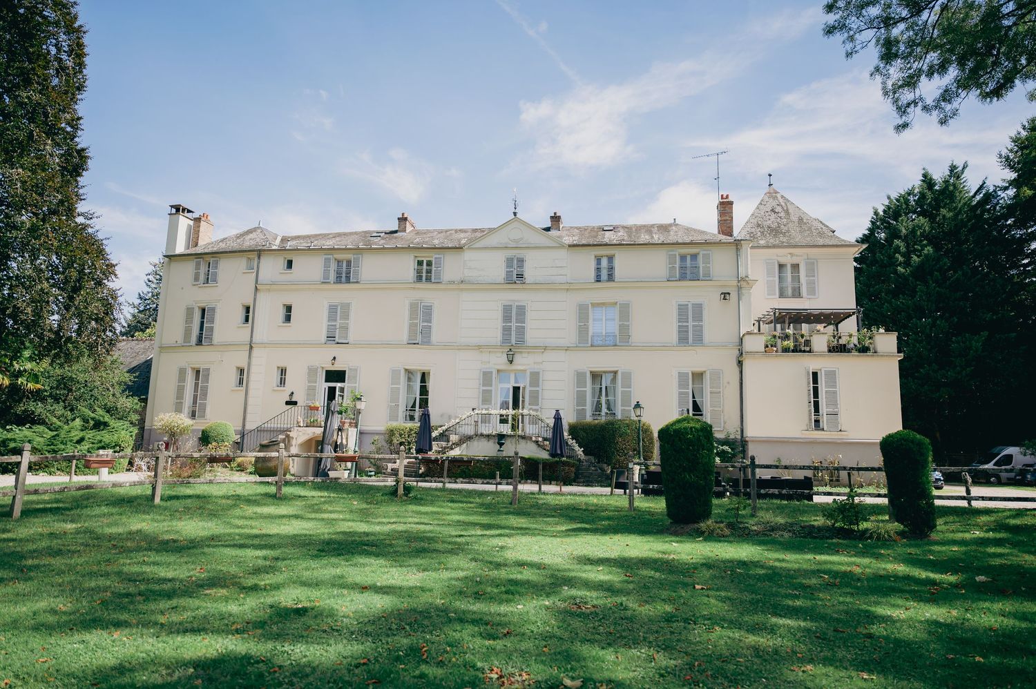 Grand French chateau wedding venue with manicured lawns and elegant architecture under a blue sky.