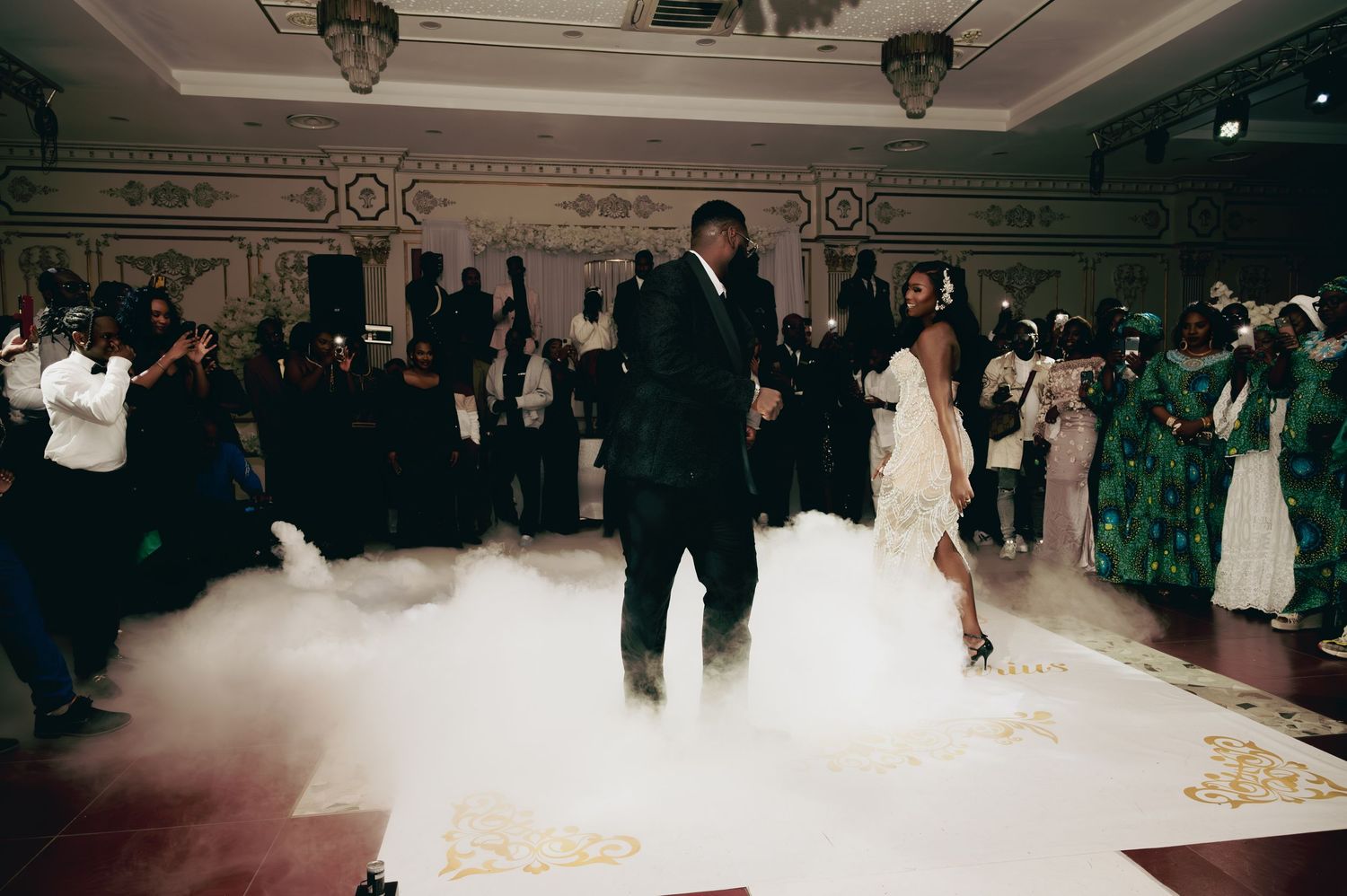 Couple shares first dance on white dance floor with dry ice fog effect.