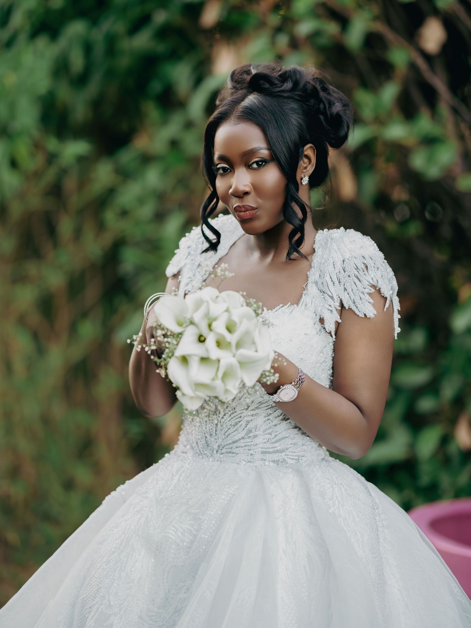 Elegant bride holds white calla lily bouquet wearing a feathered lace wedding ball gown.
