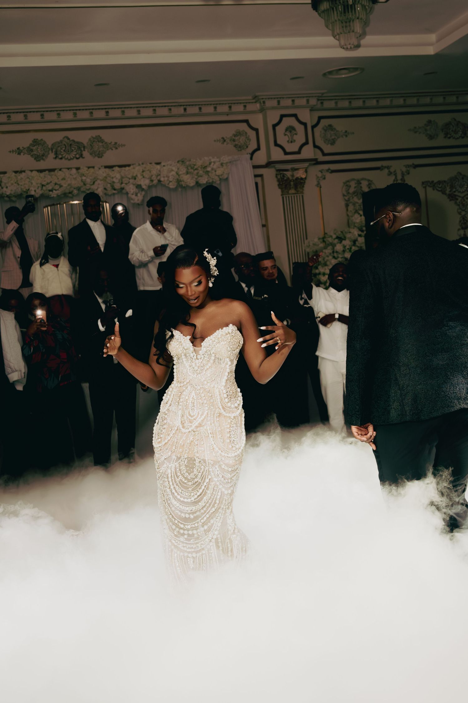 Bride in beaded strapless gown dances in dramatic dry ice fog at reception.