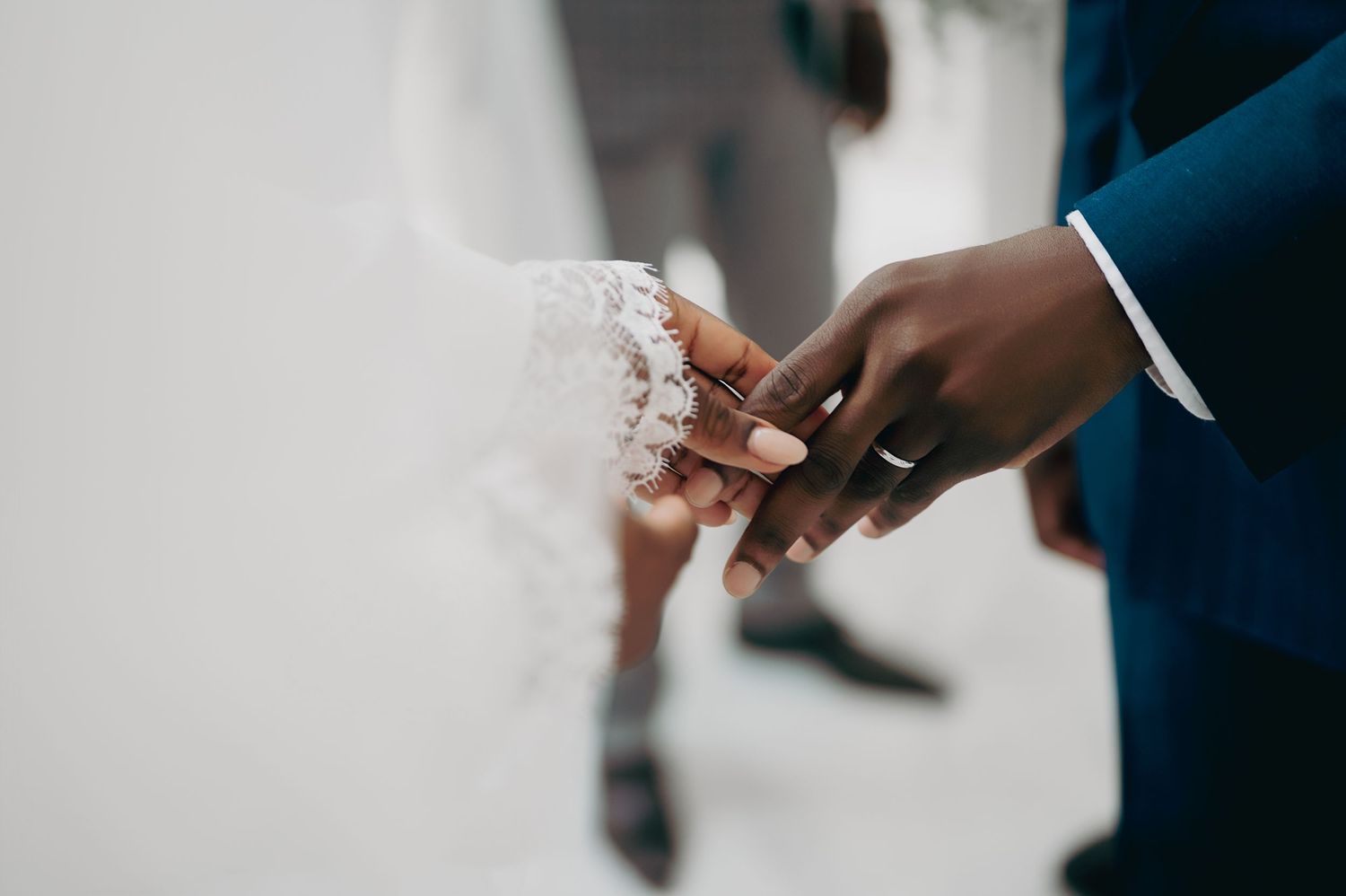 Close-up of groom placing wedding ring on brides hand during an elegant wedding ceremony.