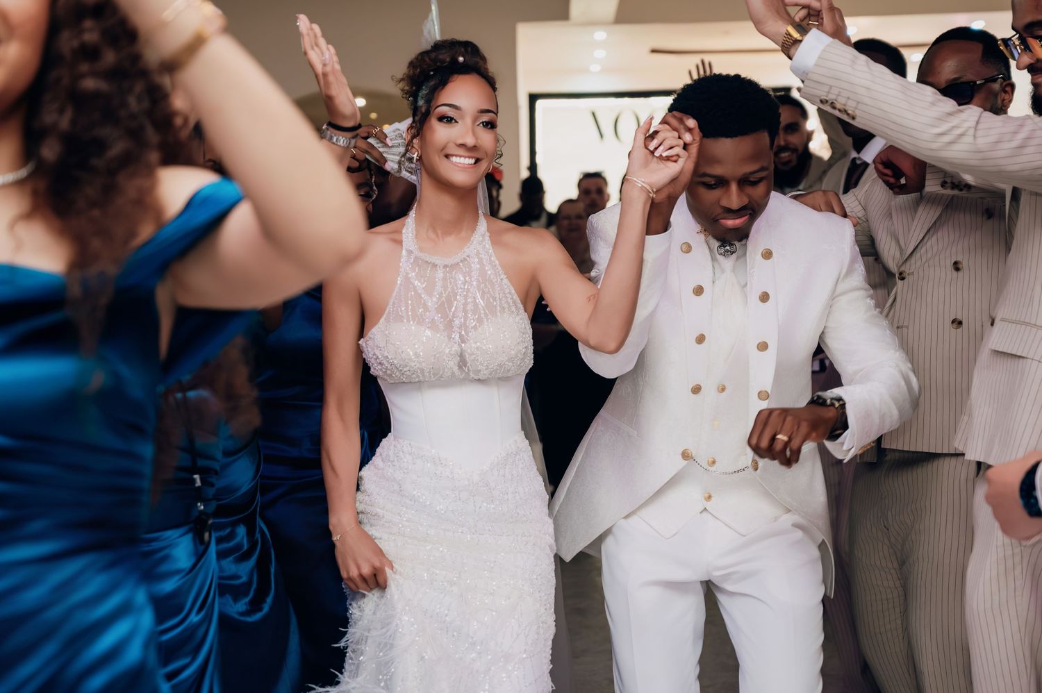 Newlyweds dancing joyfully at their Vogue-themed wedding reception with guests.