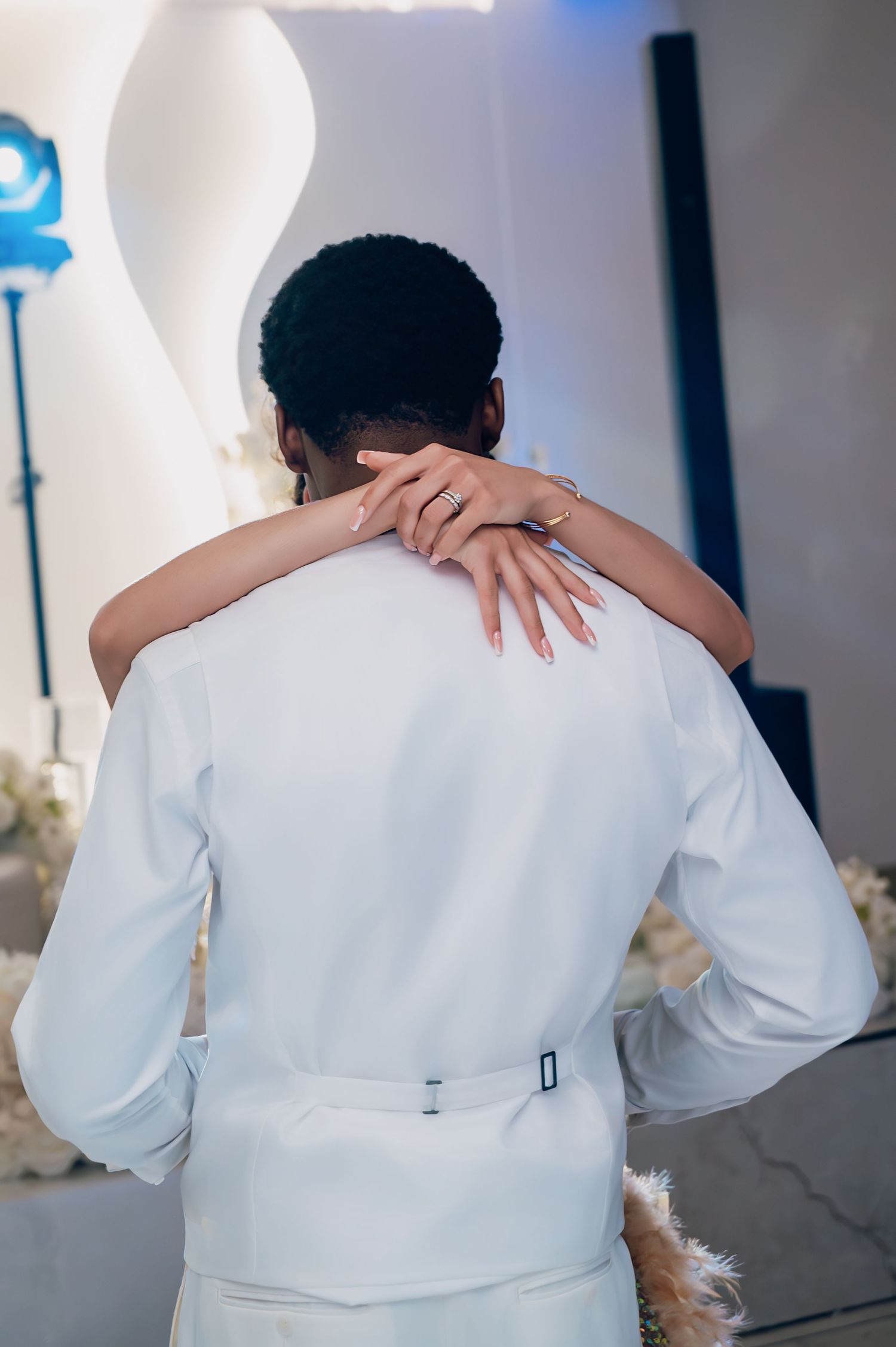 Close-up of bride resting hand on grooms white suit jacket during wedding first dance.