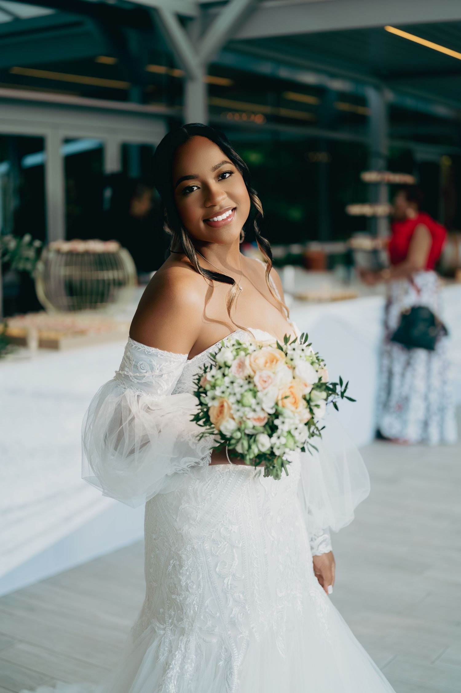 Radiant Black bride in off-shoulder lace mermaid gown holds peach and white bouquet.