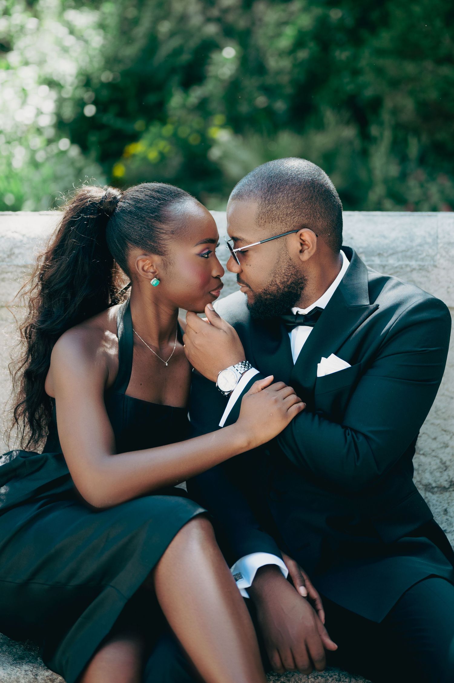 Romantic Black couple in black formal wear share a close intimate moment on stone steps.