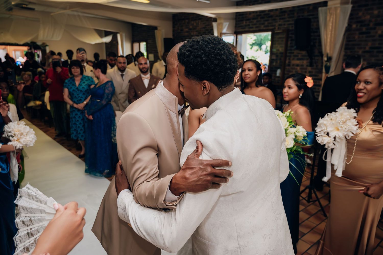 Emotional wedding ceremony moment as groom embraces a family member at the altar surrounded by guests.