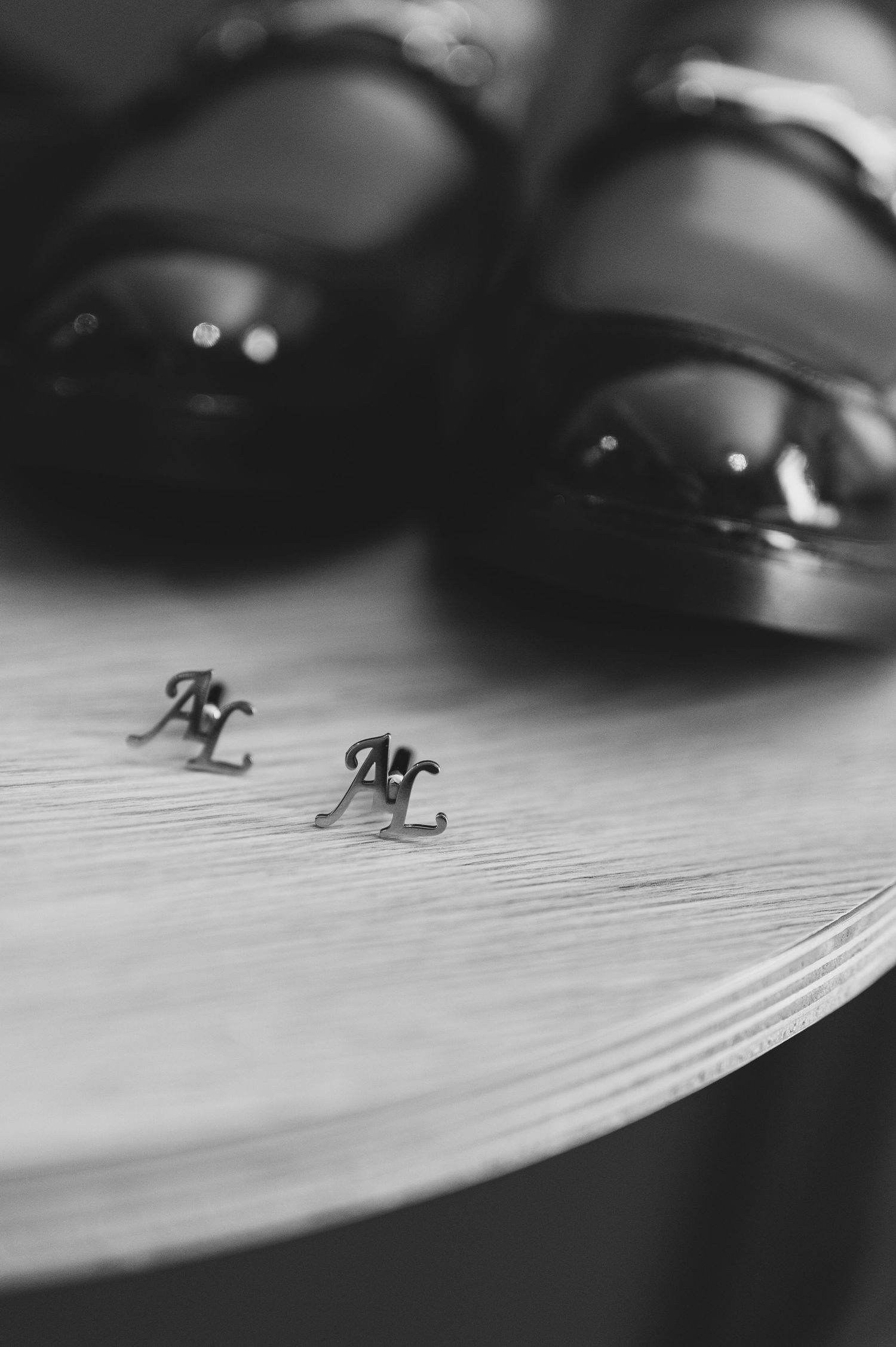 Black and white photo of monogram AL cufflinks beside polished groom dress shoes.