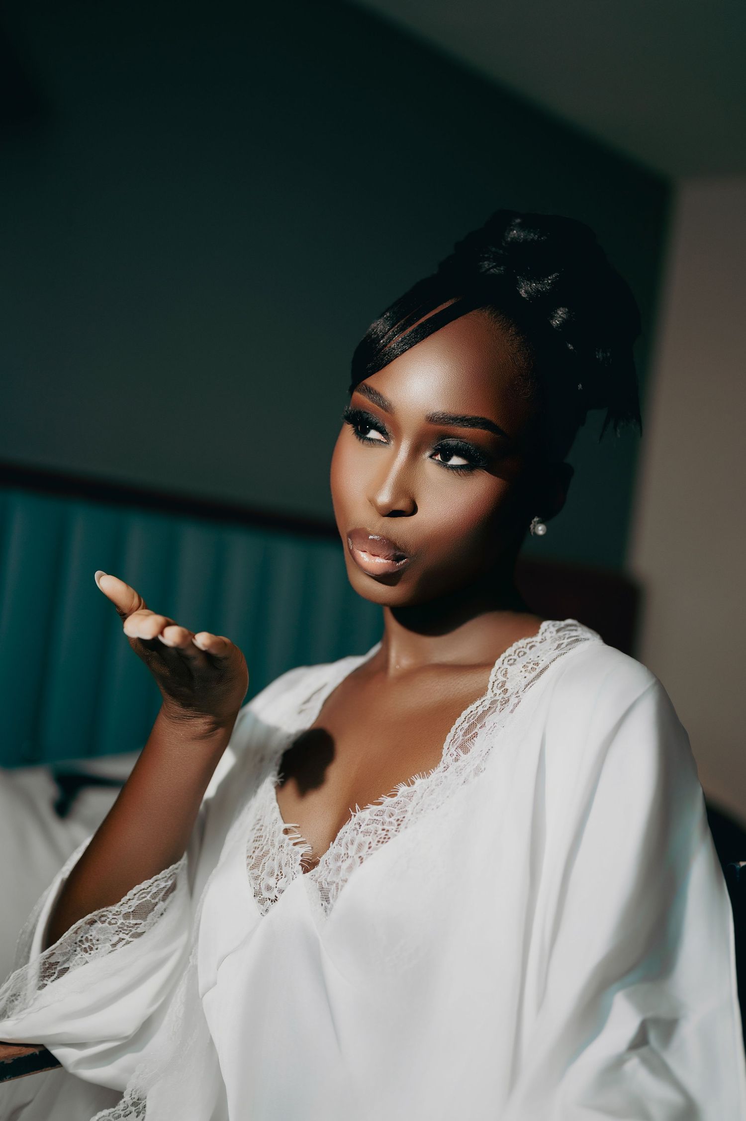 Beautiful Black bride in white lace robe blows a kiss during bridal preparations.