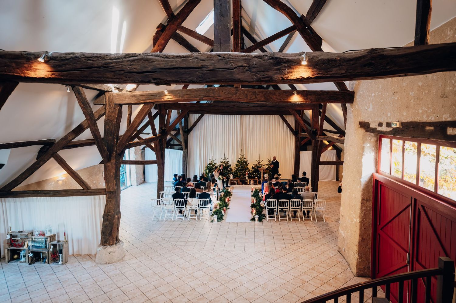 Aerial view of intimate winter wedding ceremony setup in rustic barn with exposed wooden beams.