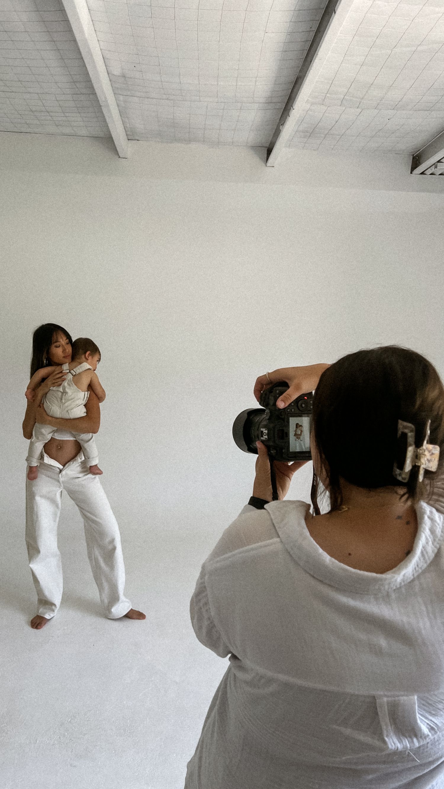 Photography session in progress showing photographer capturing subjects in white against bright studio backdrop.