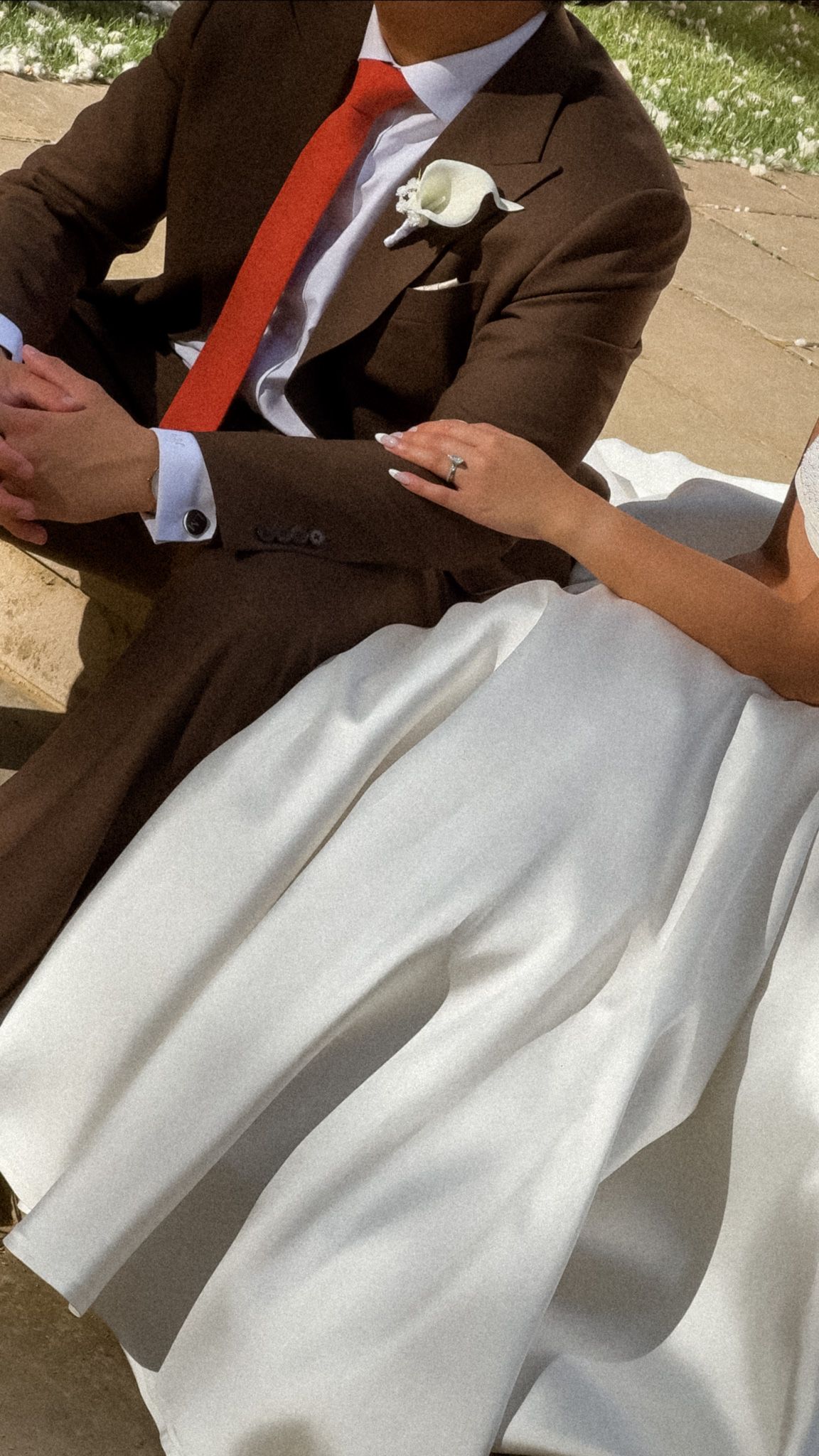 Close-up detail of a white wedding dress fabric and brown suit.