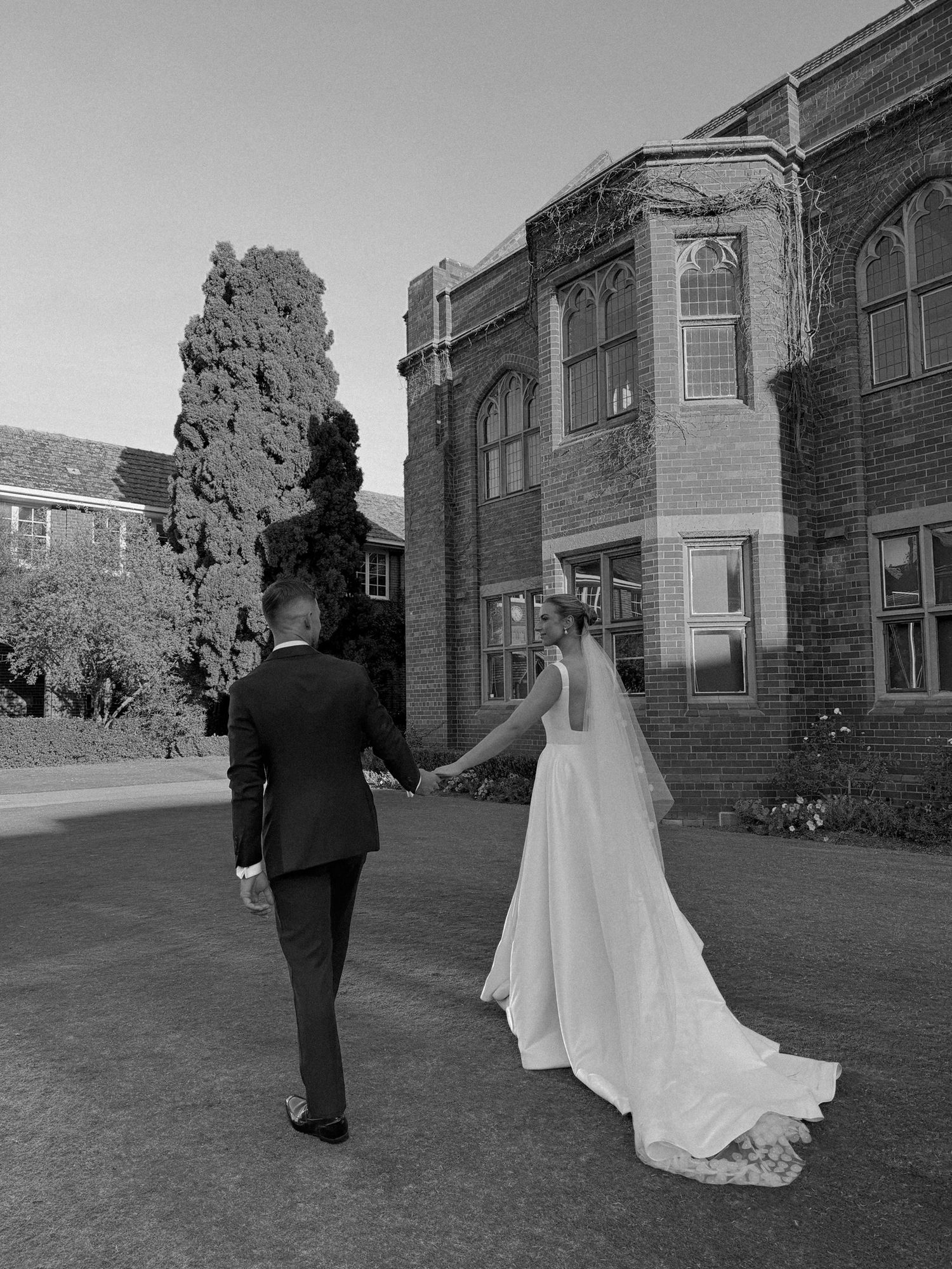 Black and white wedding portrait against historic brick building backdrop.
