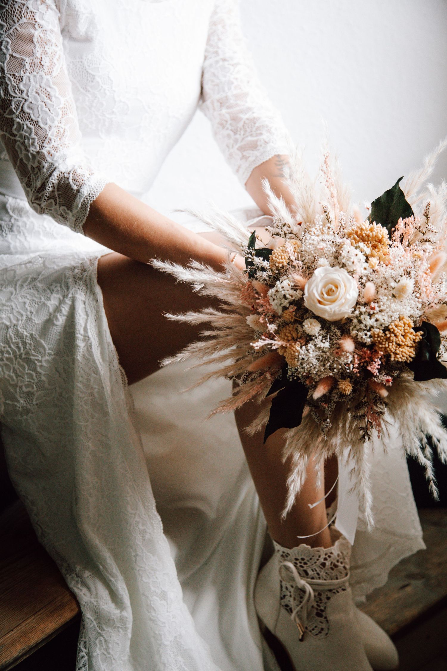 Delicate dried flower bouquet in peach and cream tones with pampas grass and roses.