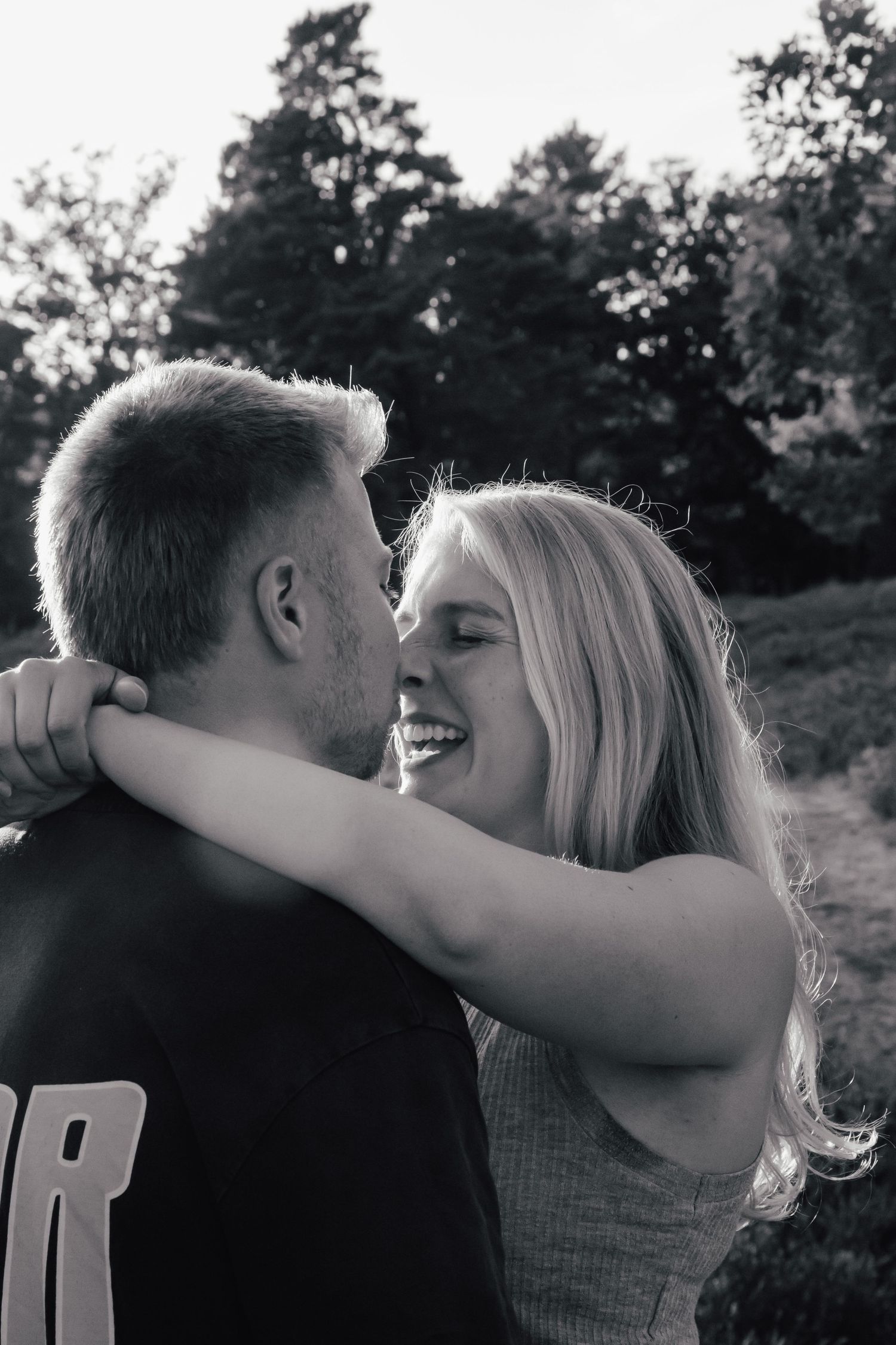 Black and white romantic moment captured in natural outdoor setting.