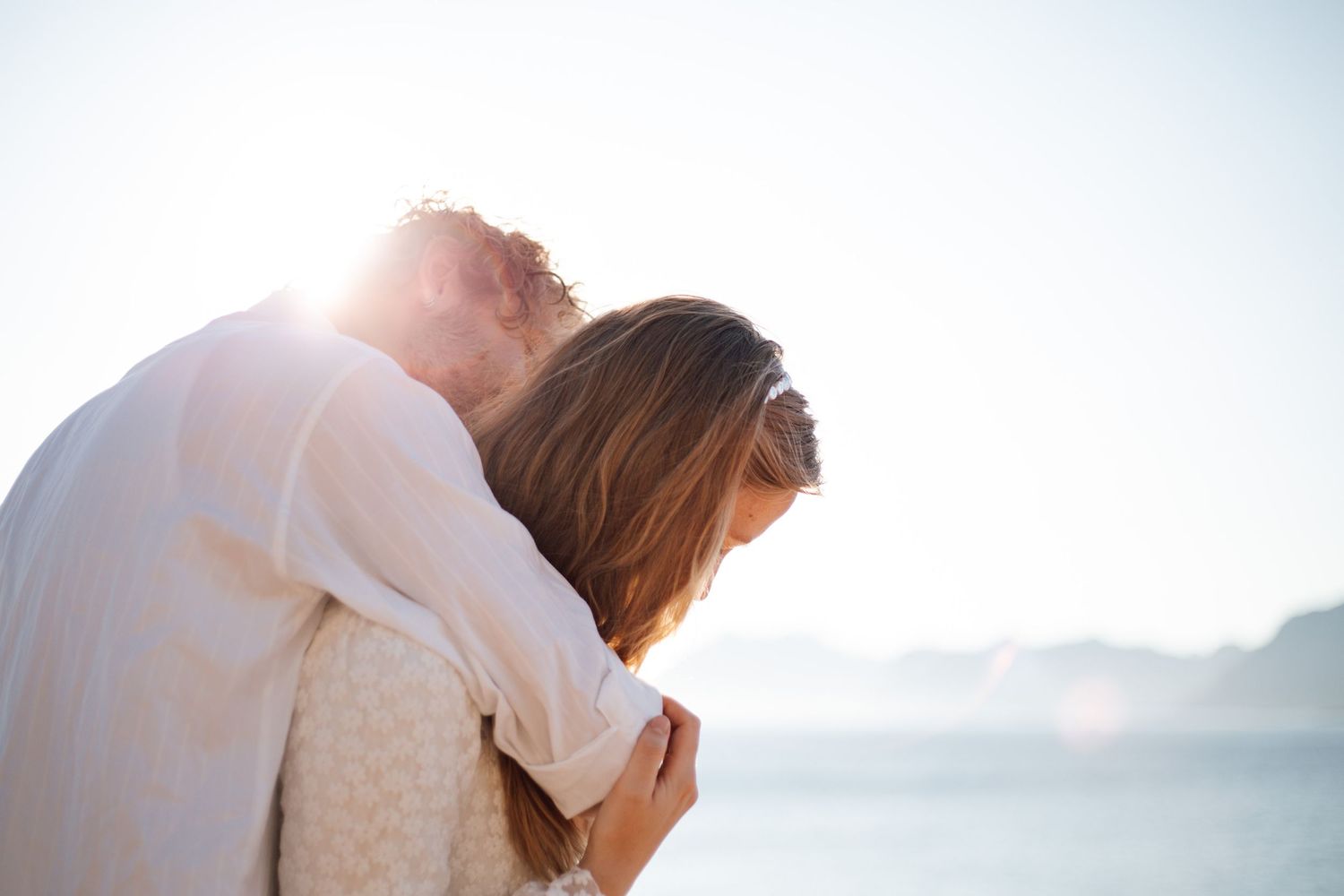 Romantic silhouettes embracing against misty mountain backdrop at sunset.