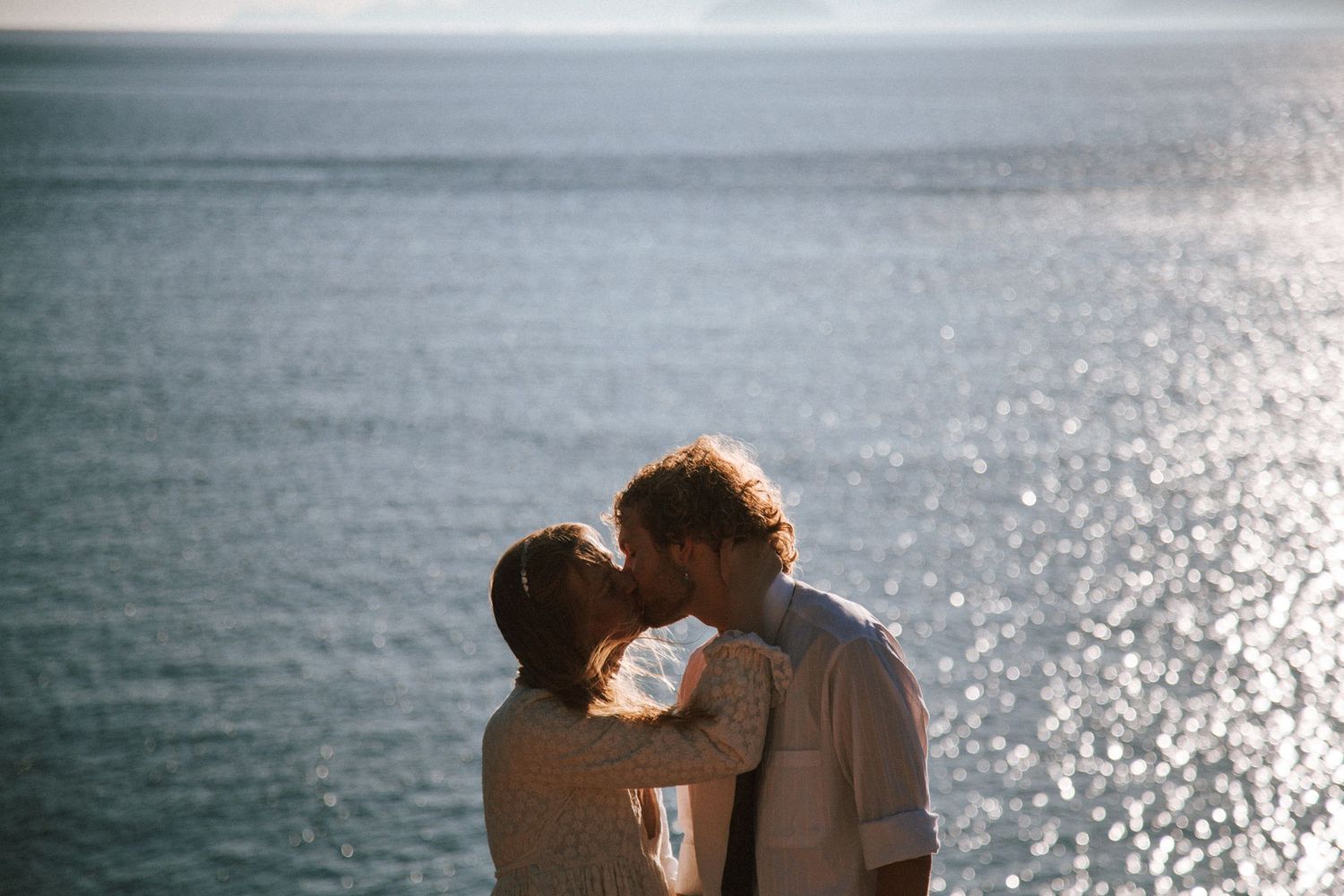 Romantic silhouettes against sparkling ocean backdrop at sunset.