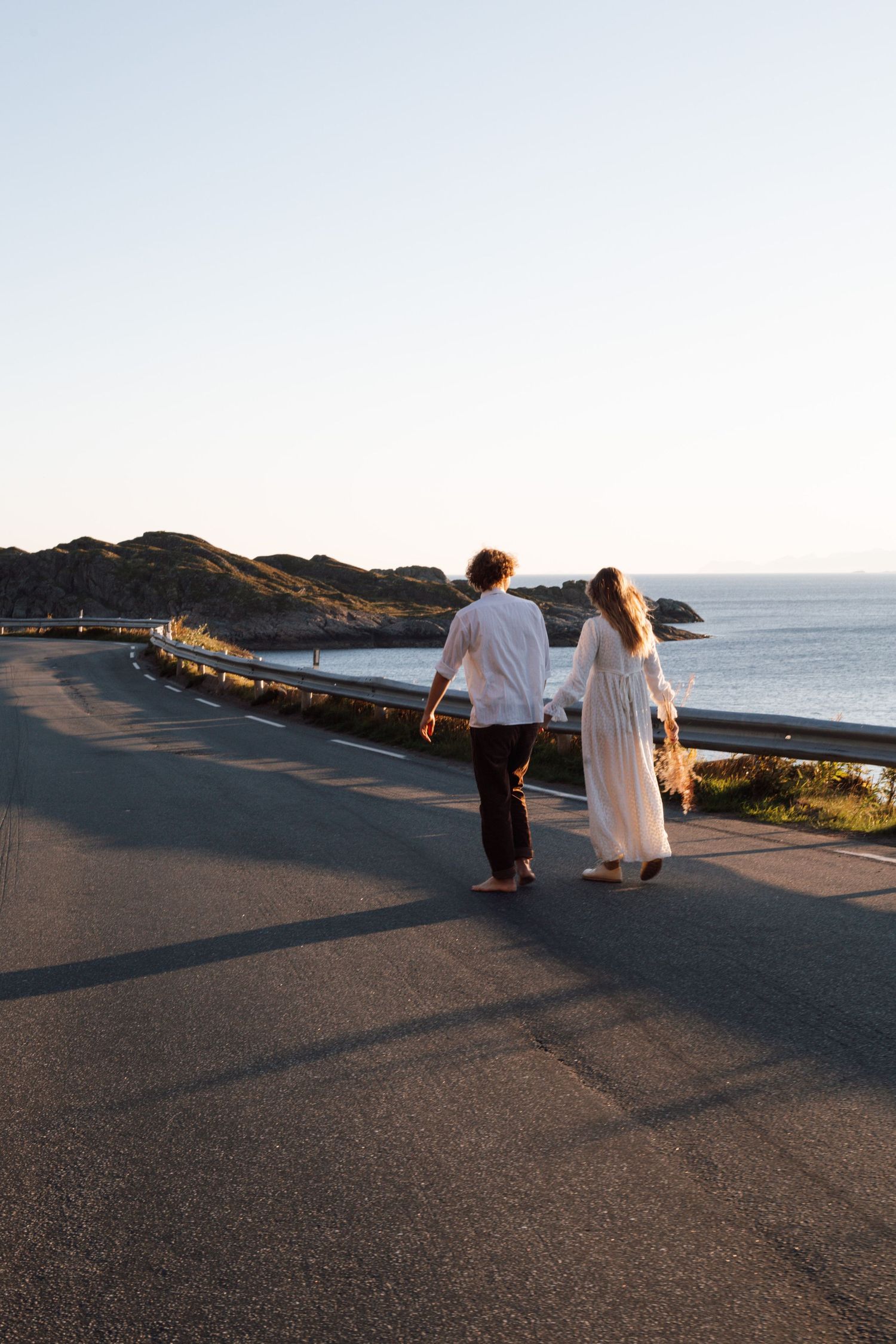 Couple walking along a coastal path during sunset with ocean views.